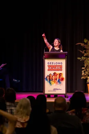 Young person on stage pointing.