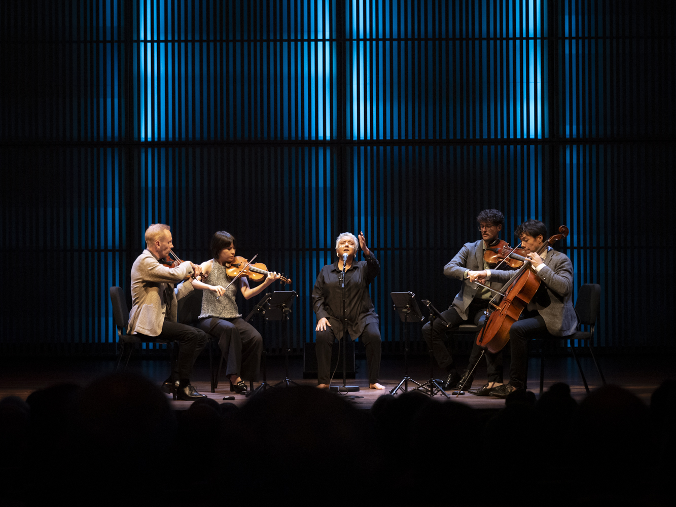Dr. Lou Bennett AM performing with string quartet on stage